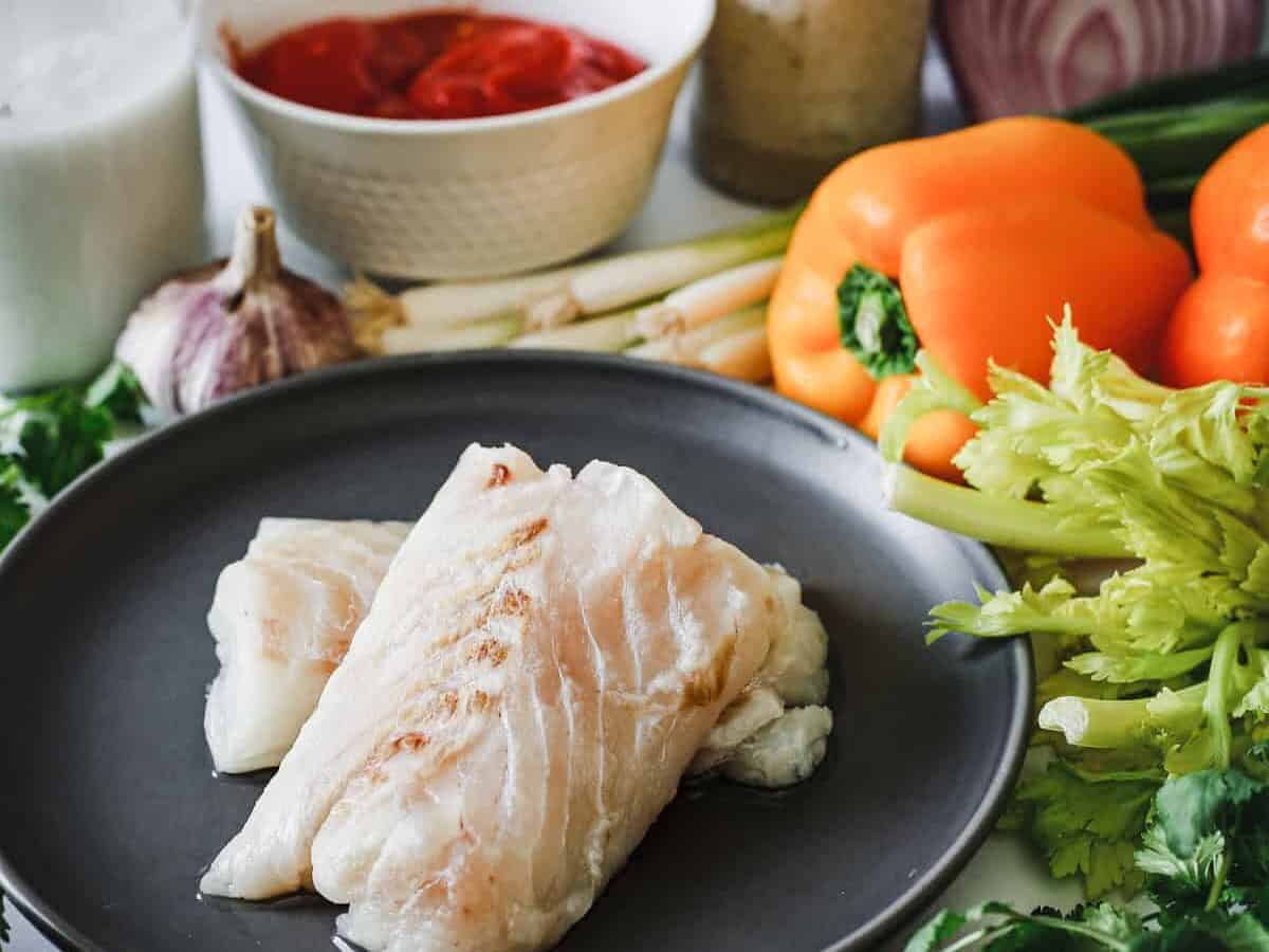 A plate of fish and vegetables on a table.