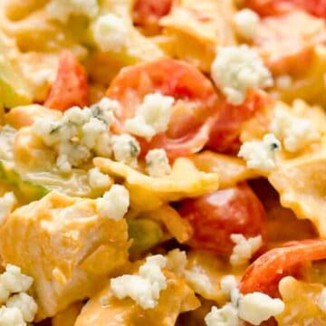 Close-up of bowtie pasta salad with cherry tomatoes, celery, chicken, blue cheese, and creamy dressing.