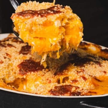 A serving spoon lifts cheesy, golden baked macaroni and cheese with a crispy breadcrumb topping from a casserole dish—perfect for easy dinners.