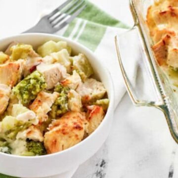 A bowl and dish of creamy chicken and broccoli casserole on a green-striped napkin with a fork.