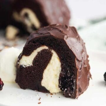 A slice of chocolate bundt cake with cream filling, served with blackberries and a scoop of vanilla ice cream.