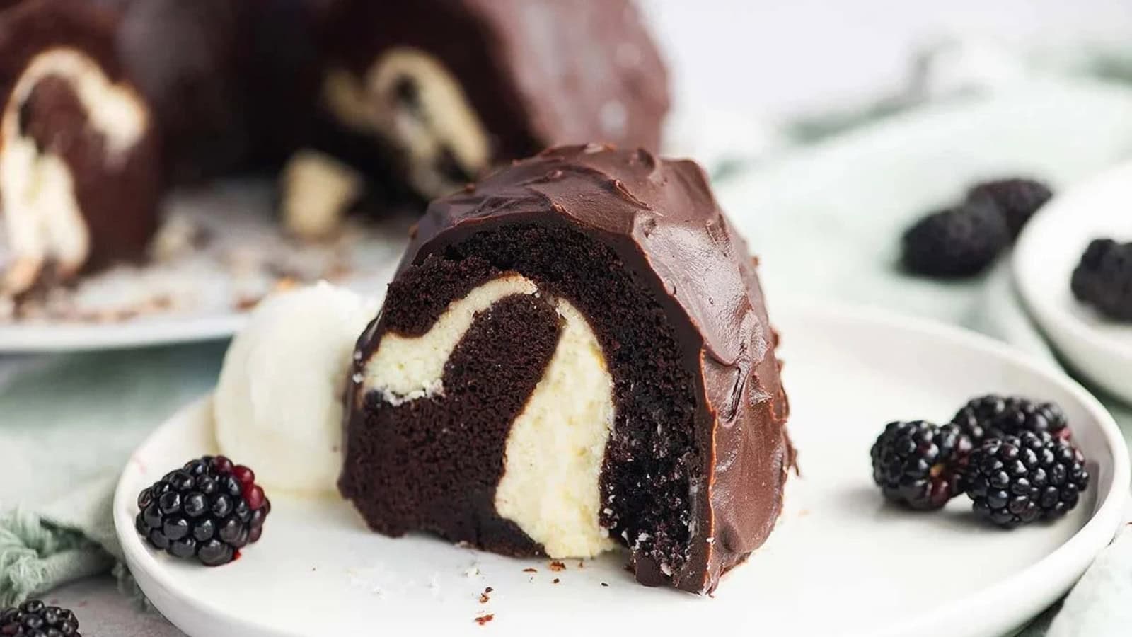 A slice of chocolate bundt cake with cream filling, served with blackberries and a scoop of vanilla ice cream.
