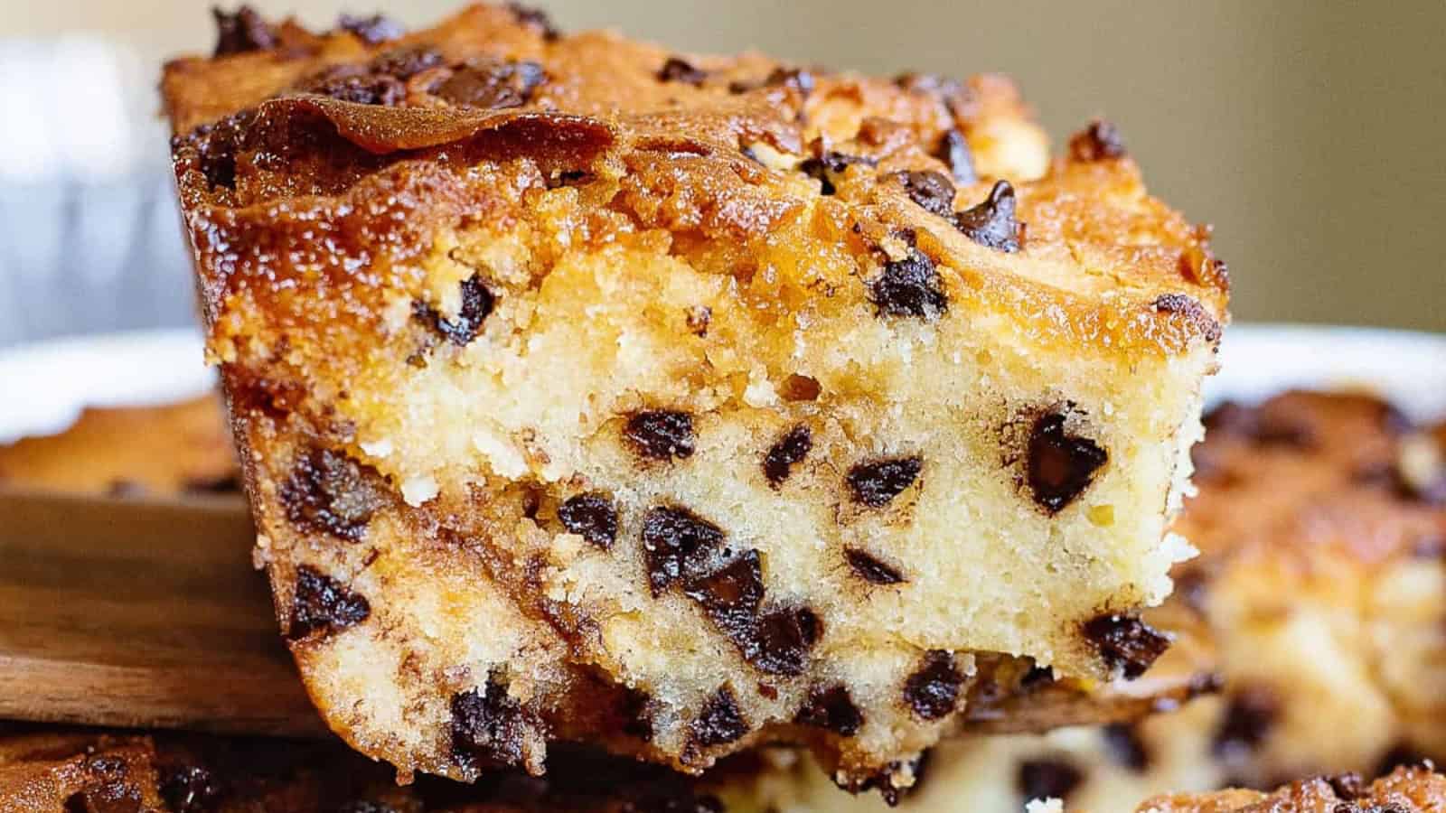 A close-up of a thick, moist chocolate chip cookie bar on a spatula.