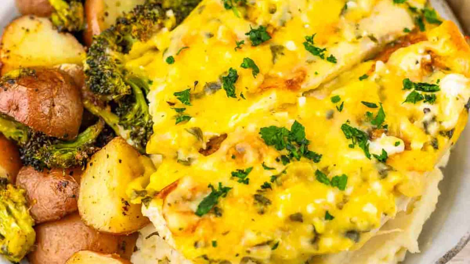 Chicken breast topped with melted cheese and herbs, served with roasted potatoes, broccoli, and mashed potatoes.