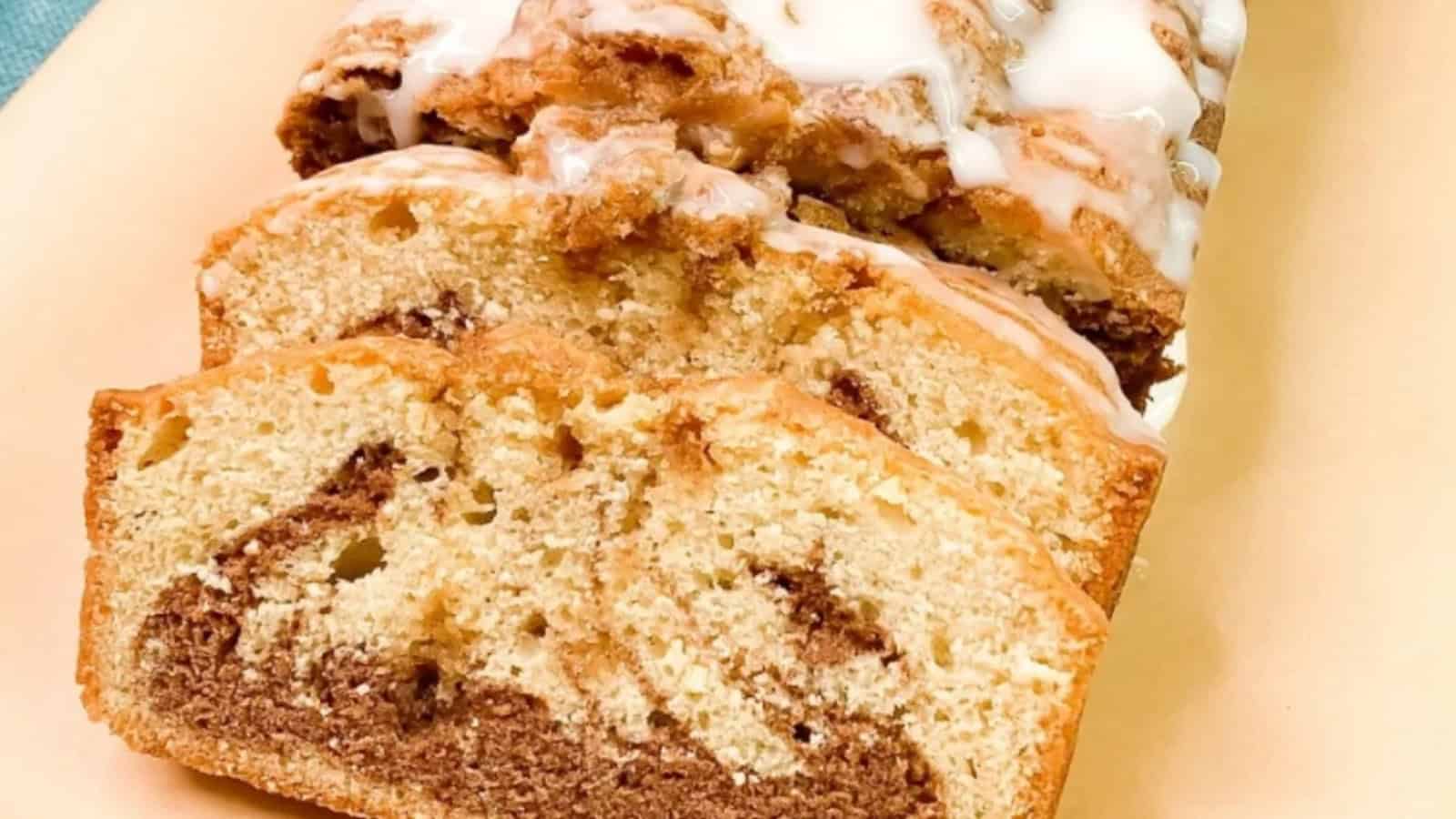 Sliced marble loaf cake with a light glaze on top, showing swirls of chocolate and vanilla inside.