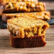A close-up of two slices of moist banana bread stacked on a wooden surface.