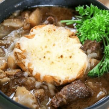 A bowl of French onion soup with bread, melted cheese, and parsley, served with slices of baguette—a true favorite among classic recipes.