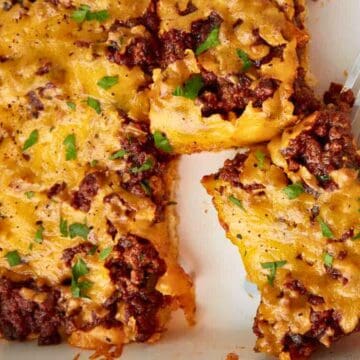 A baked dish with ground beef and melted cheese, with a slice being lifted by a spatula.