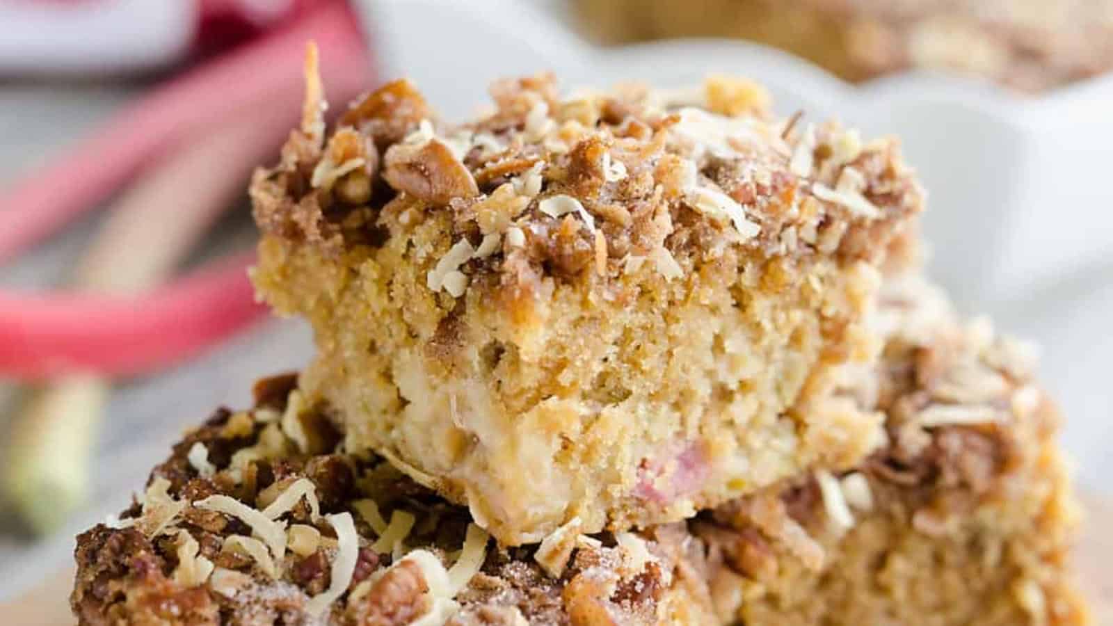 A close-up of crumbly coffee cake squares with a streusel topping, stacked on top of each other.