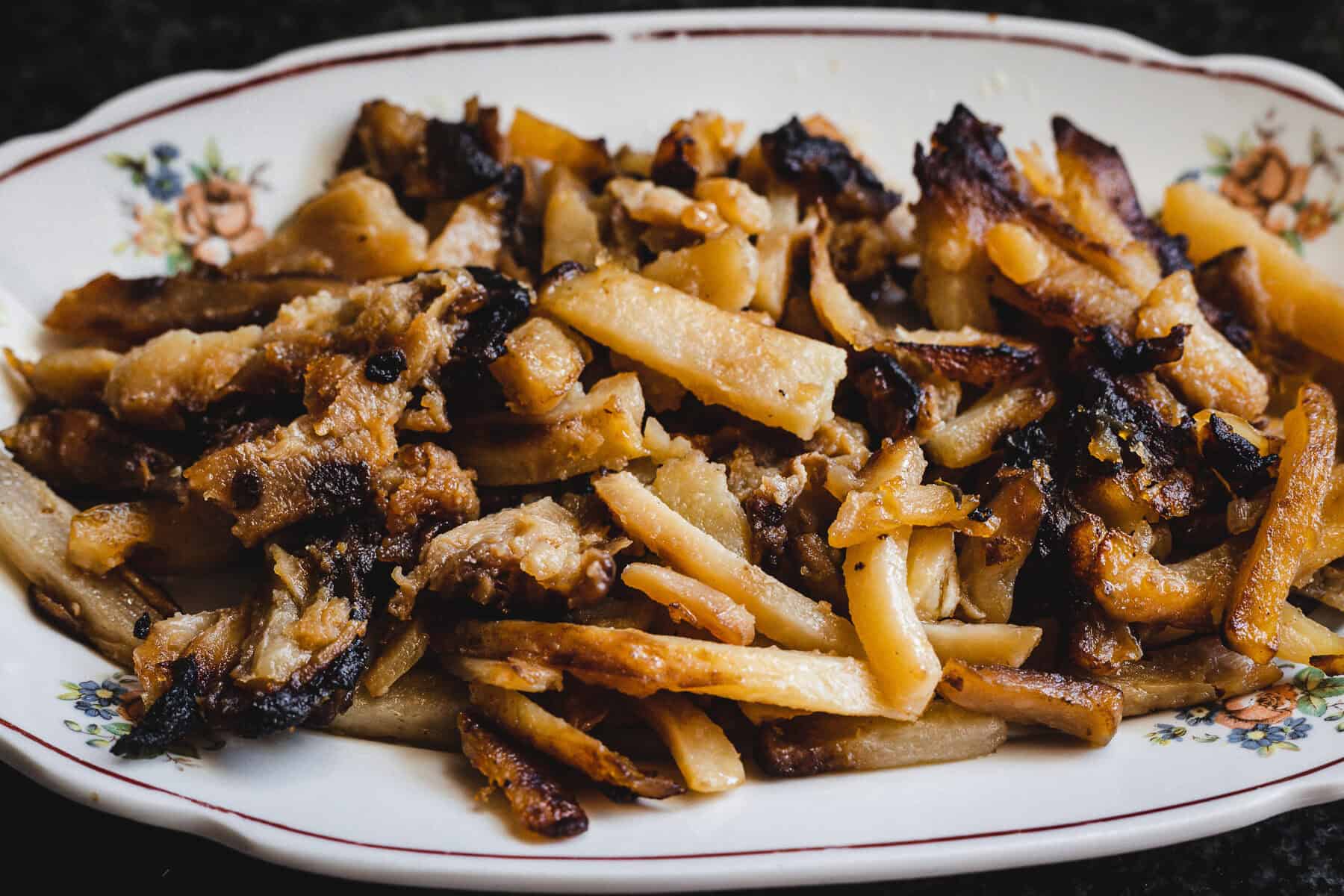 A plate of crispy, browned Russian Fried Potatoes sits on a floral-patterned dish.