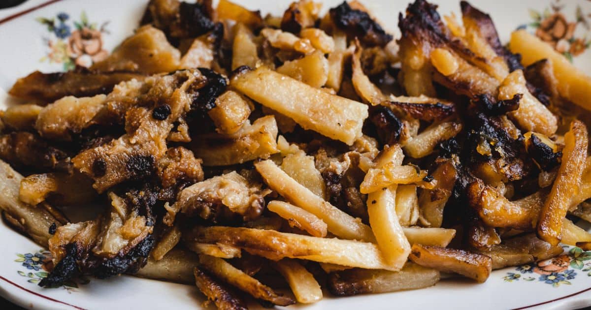 A plate of browned, crispy fried potatoes and onions on a floral-patterned dish.