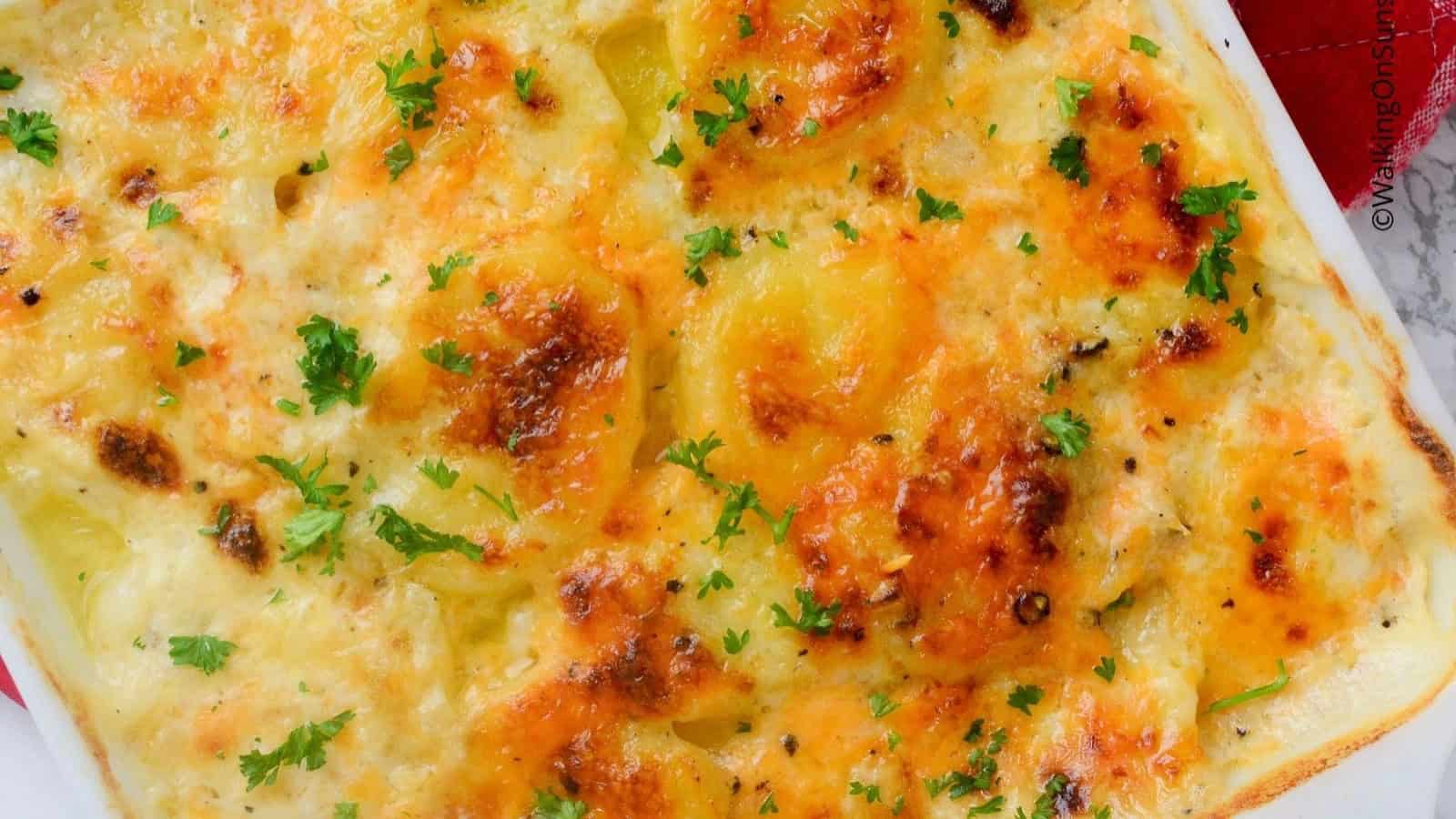 Golden, cheesy potato gratin topped with chopped parsley in a white baking dish&mdash;an irresistible addition to your favorite side dishes.