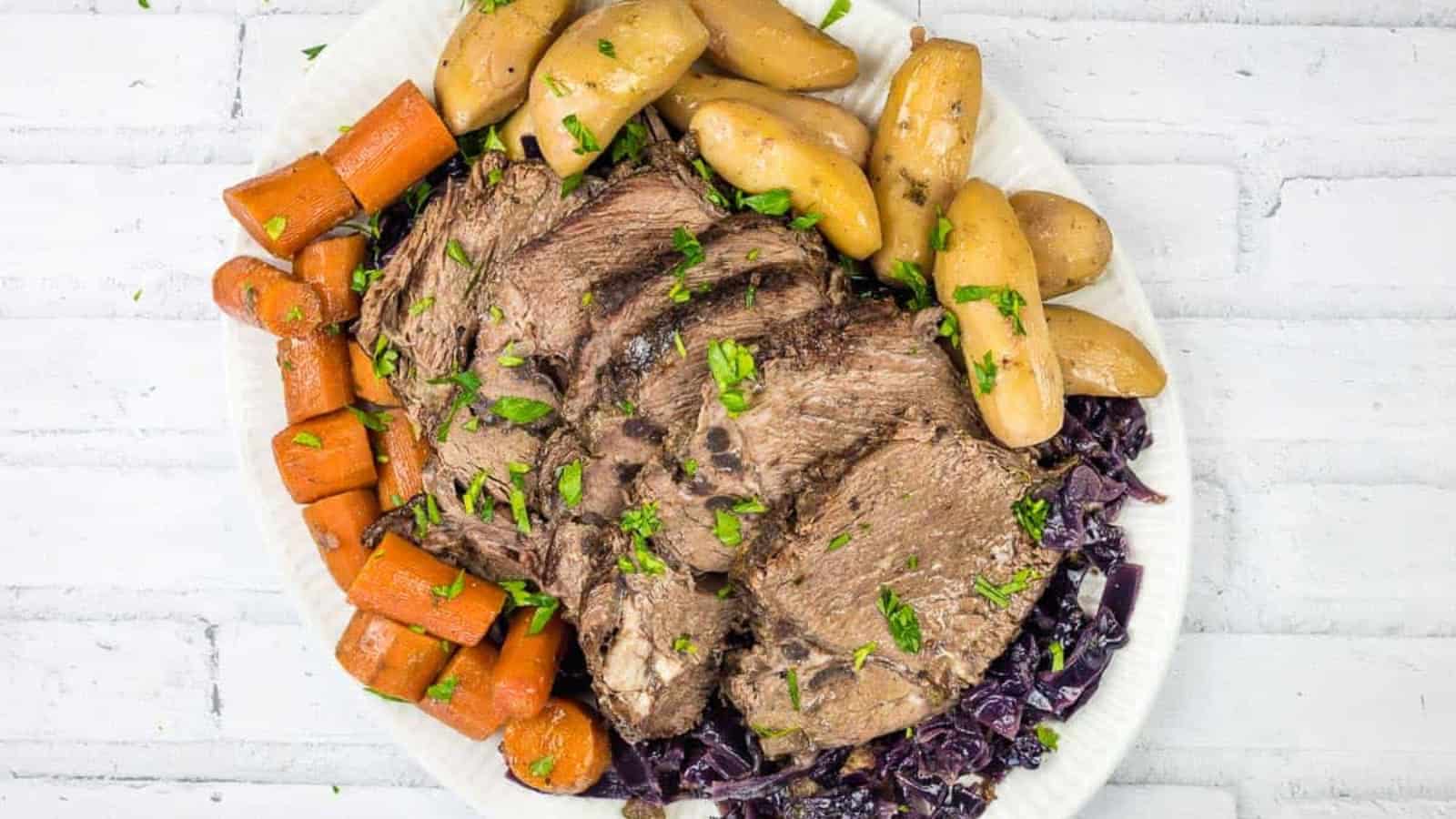 A plate of German pot roast beef with a sauce being poured over it.