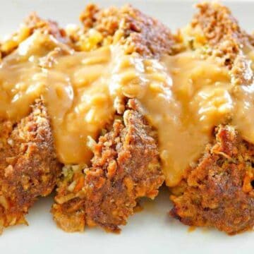 Sliced meatloaf topped with creamy brown gravy on a white plate—a comforting favorite inspired by classic recipes.