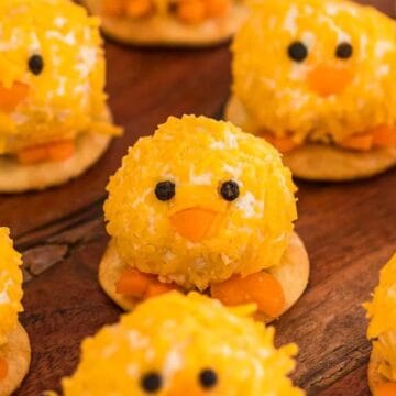Round crackers topped with cheese balls decorated to look like cute yellow chicks with candy eyes and beaks.