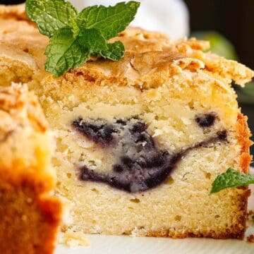 Close-up of a sliced cake with a blueberry swirl inside, topped with fresh mint leaves—perfect for make-ahead Easter brunch ideas.