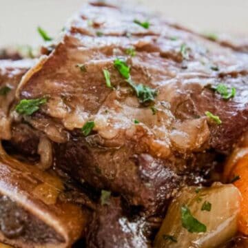 Braised short ribs with carrots, onions, and herbs, served on a bed of mashed potatoes.