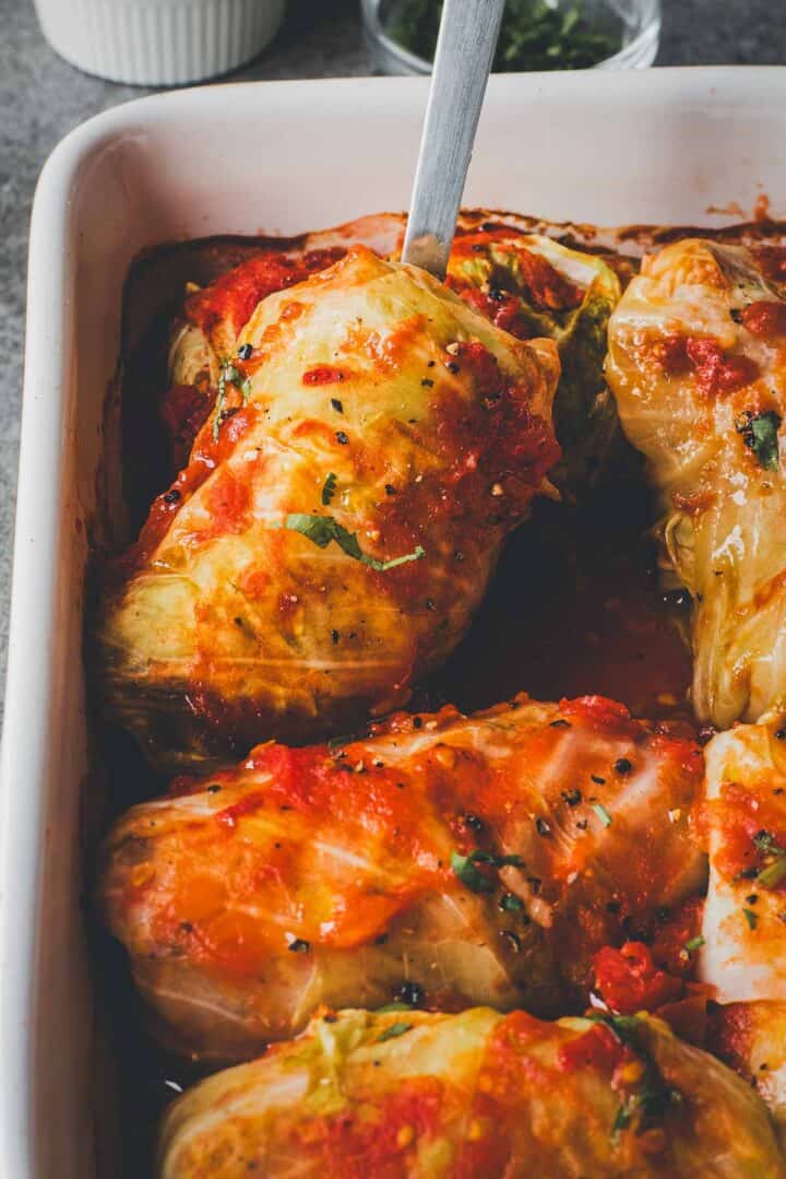 Cabbage Rolls Casserole stuffed with savory filling, topped with rich tomato sauce, served in a white baking dish with a serving spoon.