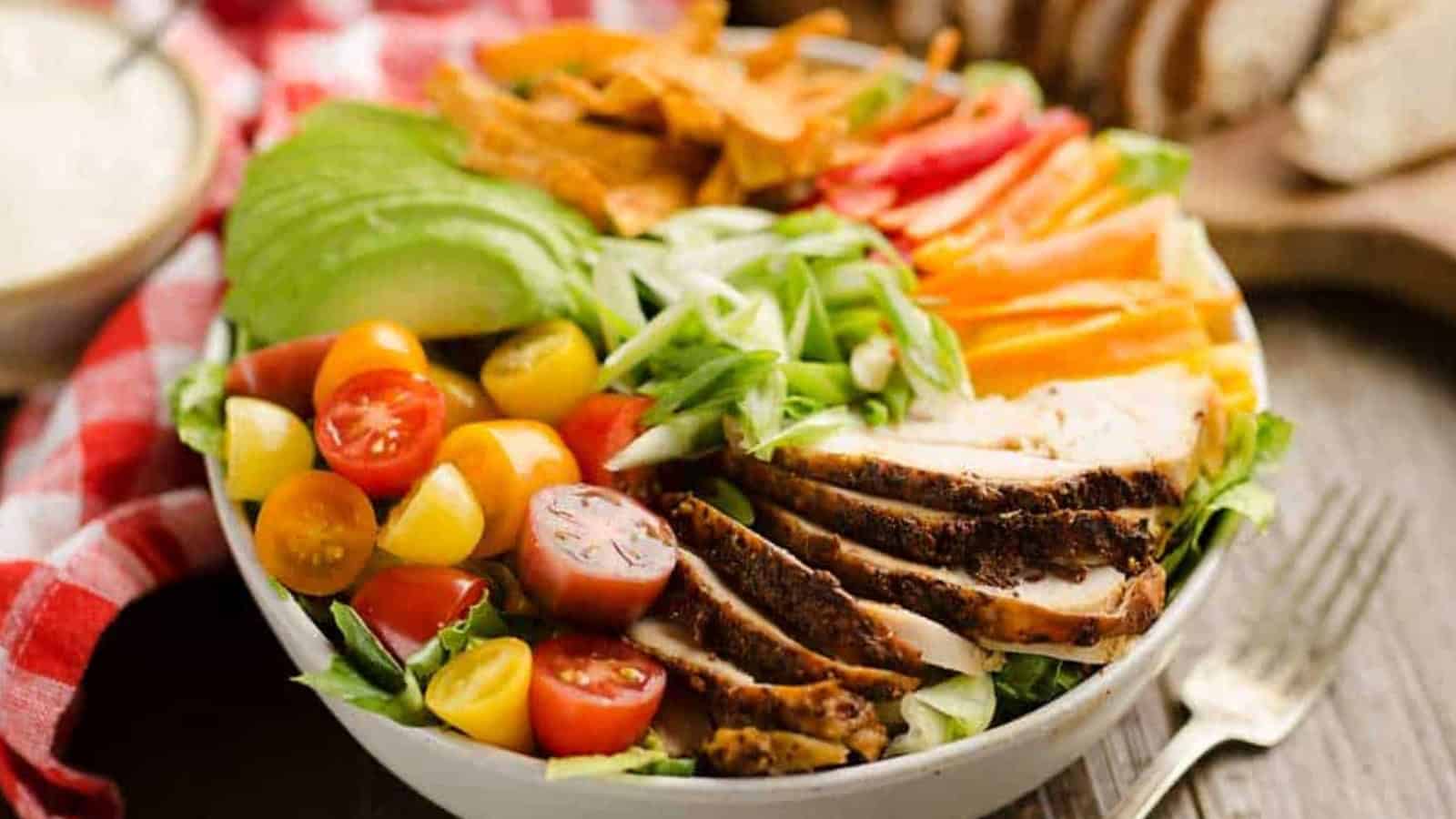 Cajun turkey salad with lettuce, tomatoes, avocado, tortilla strips, and creamy yogurt dressing.