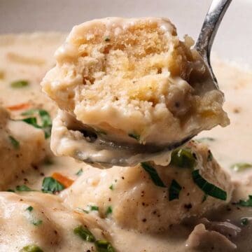 A spoon lifts a fluffy dumpling from creamy chicken and dumplings soup, garnished with fresh herbs—a comforting nod to classic depression-era recipes.