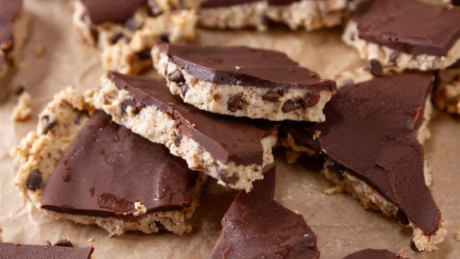 Chocolate-covered cookie dough bark pieces stacked on parchment paper—an irresistible treat perfect for fans of Vegetarian Comfort Foods.