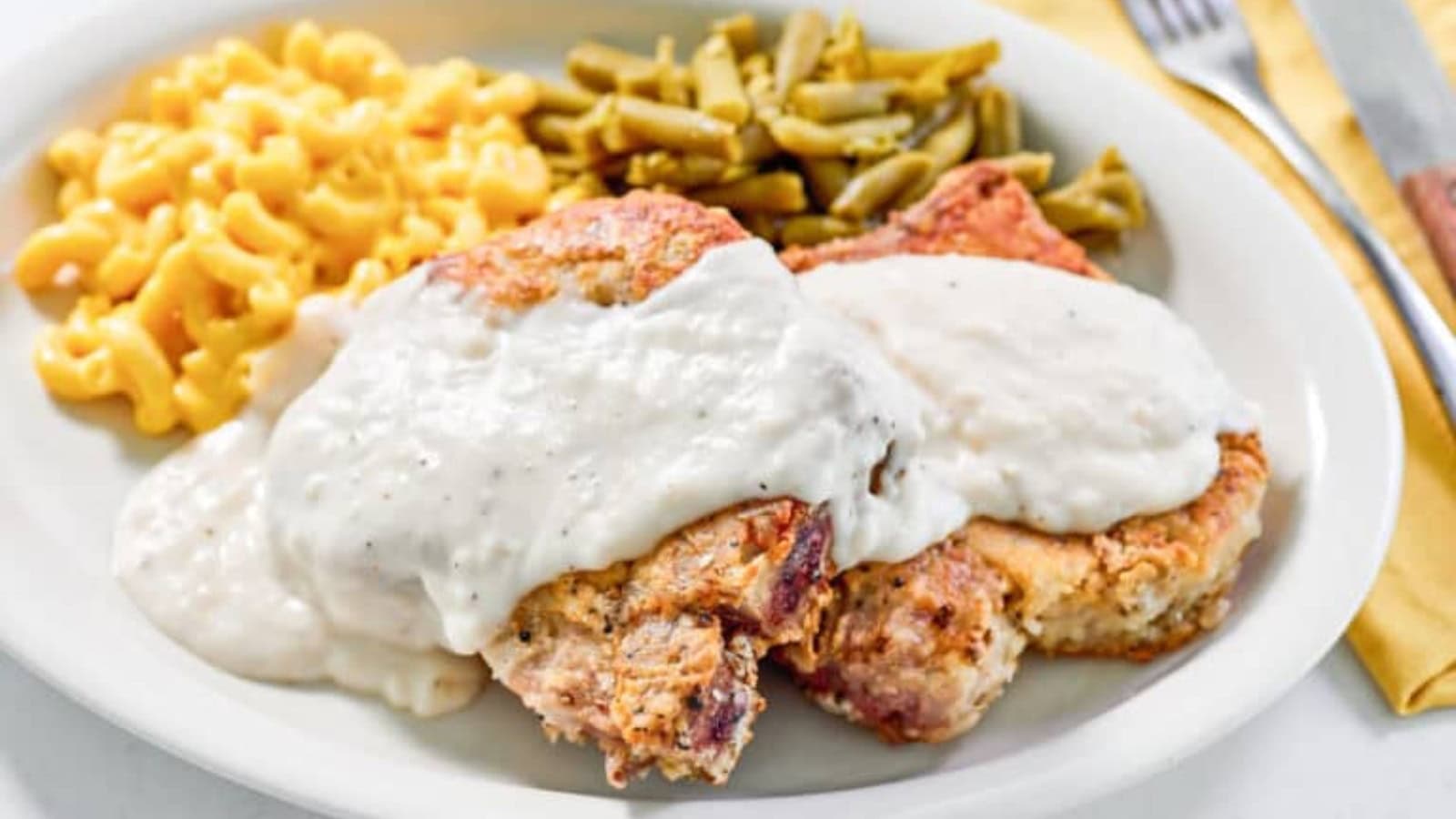 Country fried pork chops with creamy gravy served on a plate.