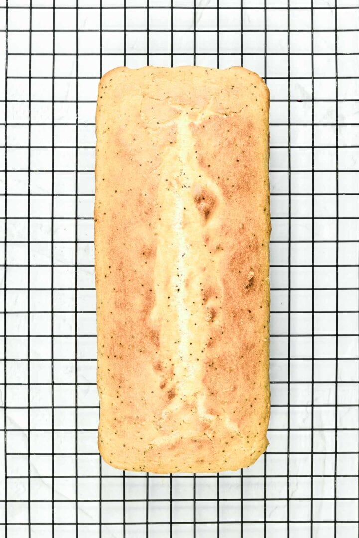 A loaf of bread cooling on a wire rack viewed from above.
