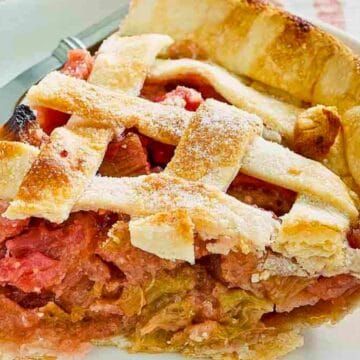 A slice of rhubarb pie with a lattice crust on a white plate, next to two forks.