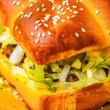 Close-up of a sandwich with sesame seed bun, lettuce, and visible beef patties.