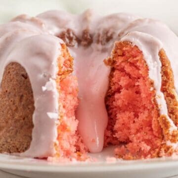 A pink bundt cake with white icing, sliced to show its moist, fluffy interior on a floral plate—a perfect choice for spring desserts.