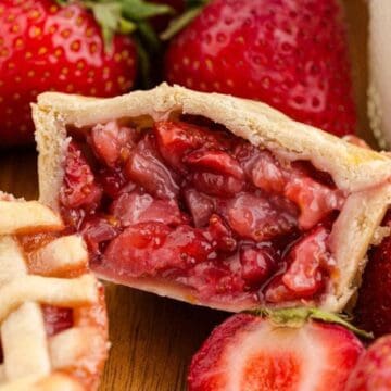A close-up of strawberry pie filling in a slice, surrounded by fresh strawberries and pie crust.