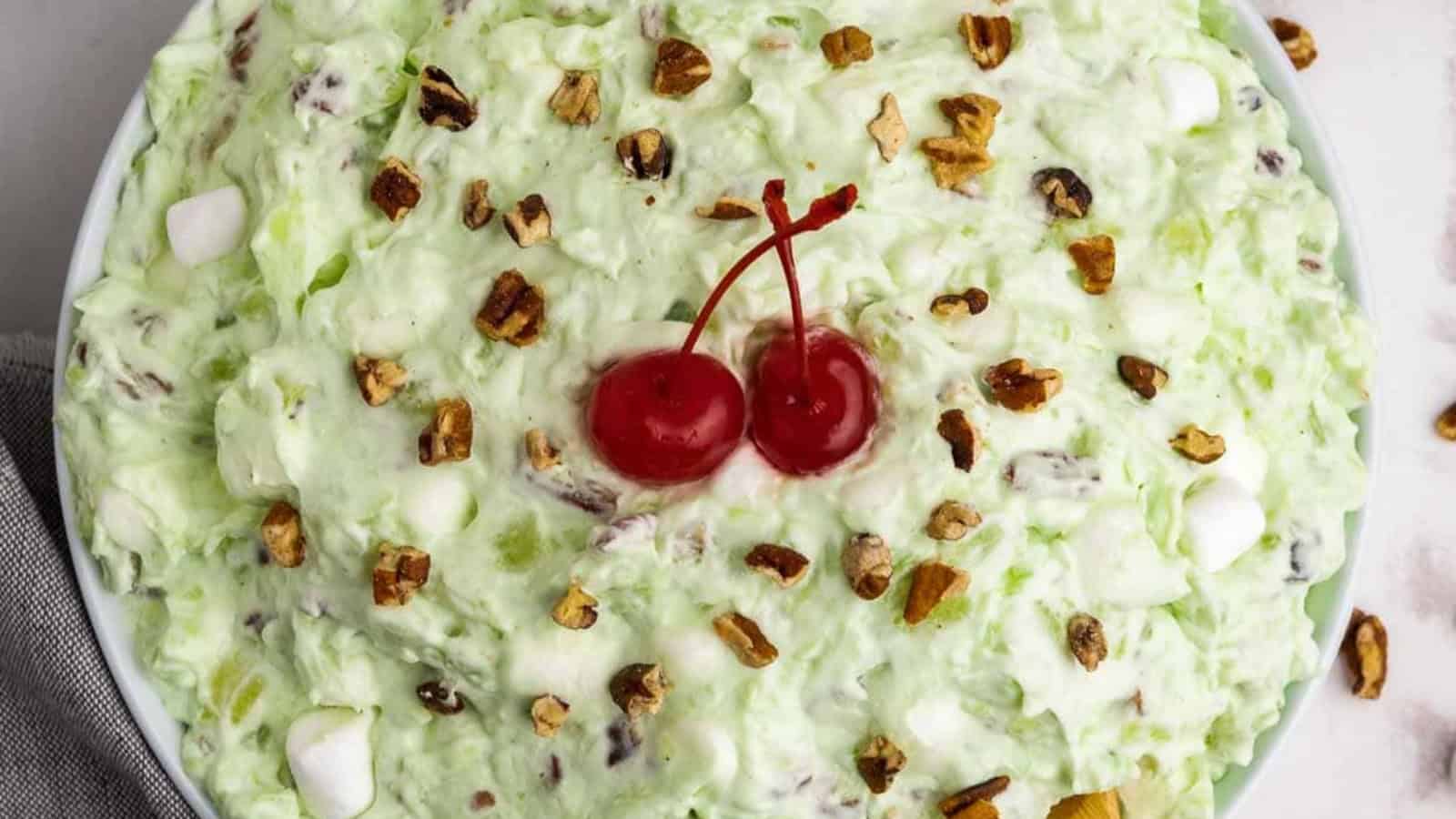 Pistachio salad topped with nuts and cherries.