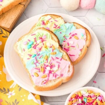 Colorful toast with pastel frosting and sprinkles on a plate, decorated with a yellow cloth and felt Easter eggs.