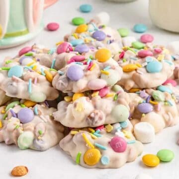 Colorful candy clusters with pastel sprinkles and mini marshmallows piled on a white surface.