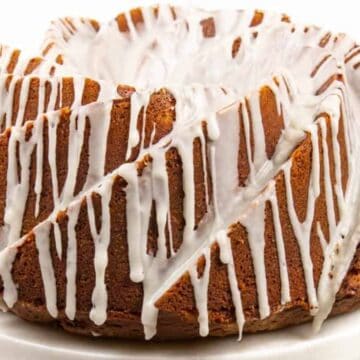Bundt cake with white icing drizzled over the top, displayed on a white cake stand—a classic choice among Kentucky Derby desserts.