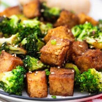 A plate of stir-fried tofu and broccoli garnished with sesame seeds.