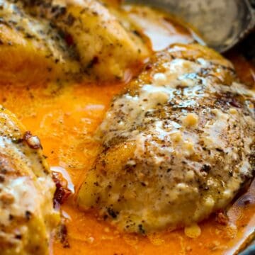 Chicken breasts cooked in a creamy orange sauce, seasoned with herbs and pepper, make for delicious high protein comfort meals—perfectly prepared in a cast iron skillet with a spoon.