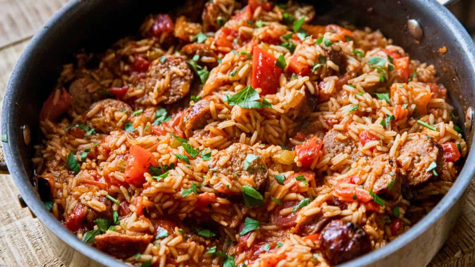 A skillet filled with cooked rice, sausage, tomatoes, and herbs, garnished with fresh parsley.