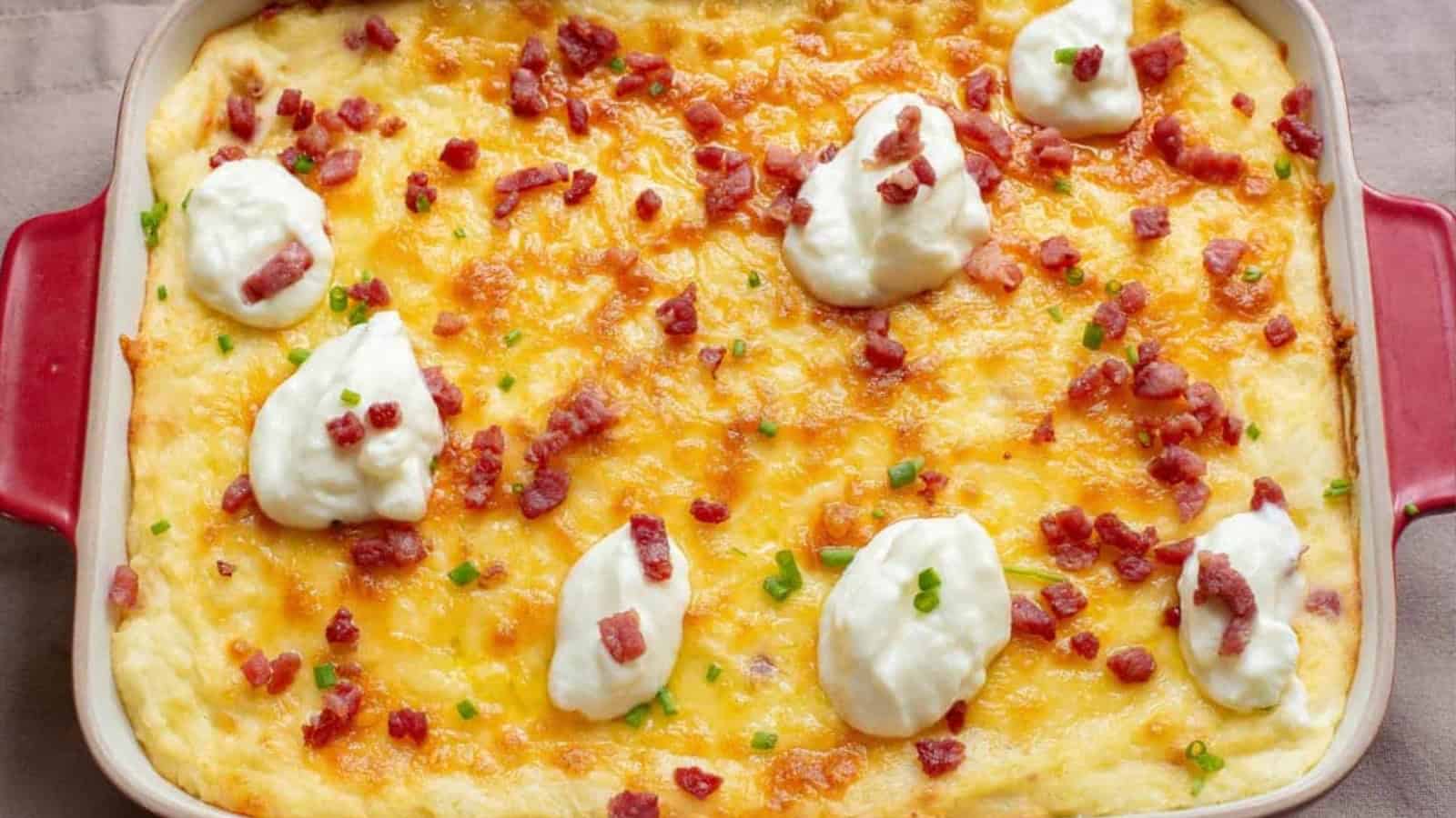 Cheesy baked casserole topped with dollops of sour cream, chopped bacon, and green onions in a red dish&mdash;one of the best easy budget side dishes for any meal.