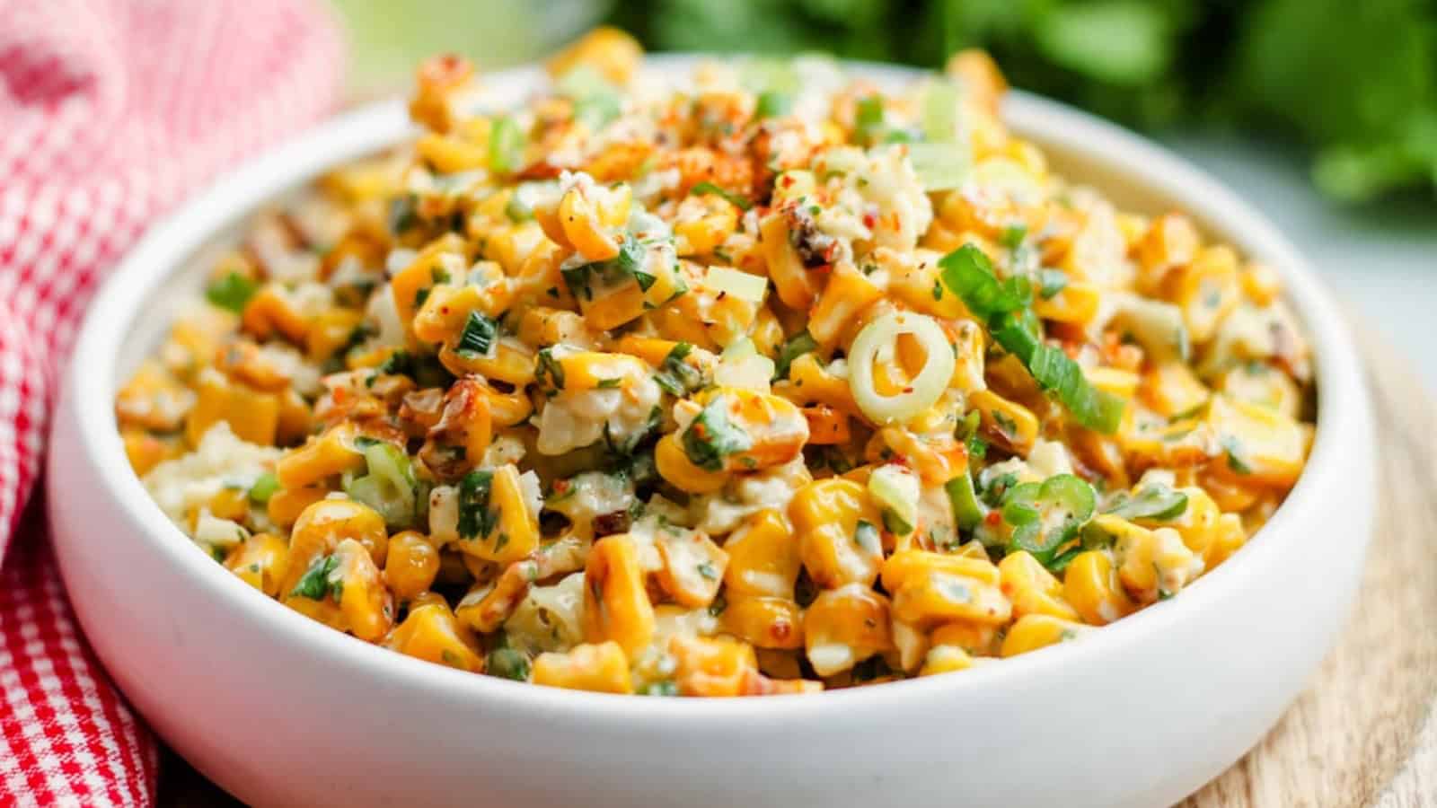 A bowl of Mexican Street Corn with a spoon in it ready to serve.
