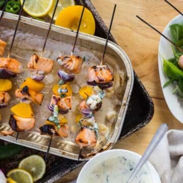 Grilled salmon and peach skewers with red onion, served with a creamy peach jalapeño sauce.
