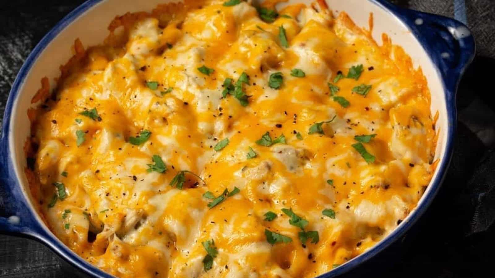 Baked casserole topped with melted cheddar cheese and garnished with chopped parsley in a blue dish.