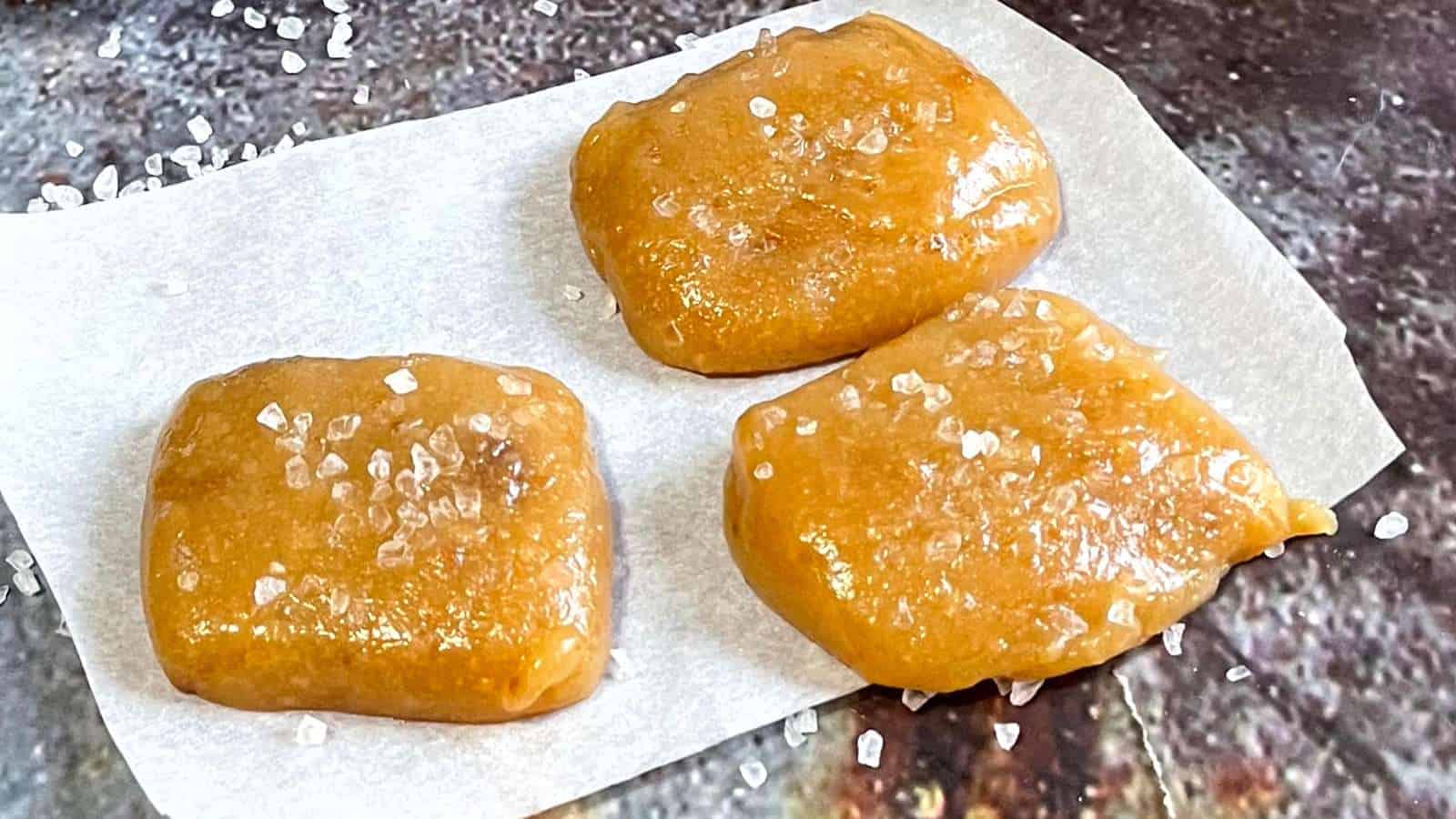 Three squares of sea salted caramel candies on a piece of paper.