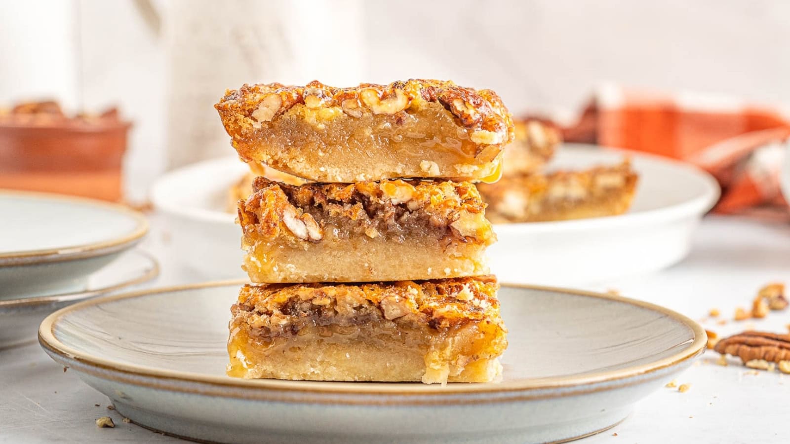Pecan dessert squares stack on top of each other.