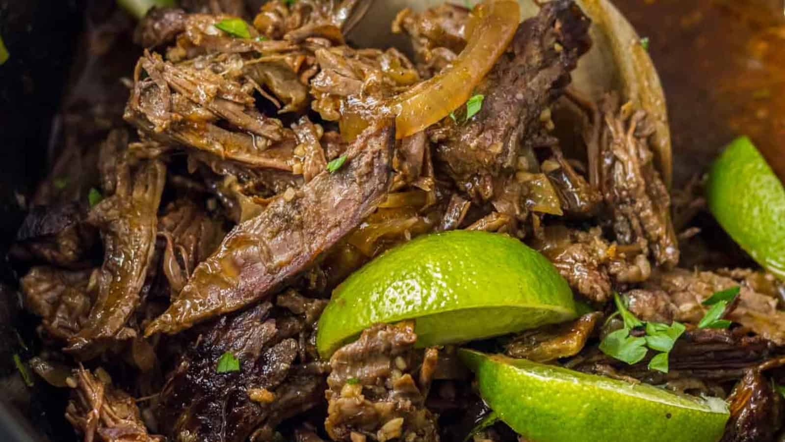 Barbacoa tacos on a tray topped with peppers and onions.