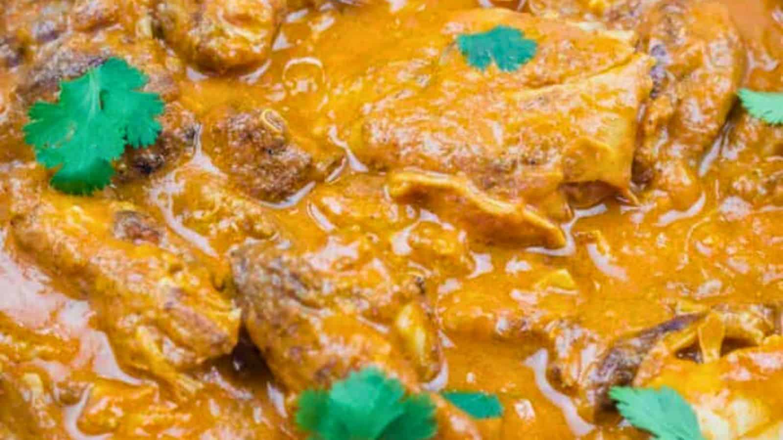 A rectangular plate of Chicken Tikka Masala with herbs on top.