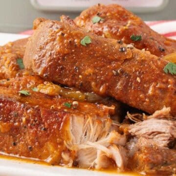 Tender, saucy pork ribs garnished with herbs, served on a white plate with visible juicy, shredded meat.