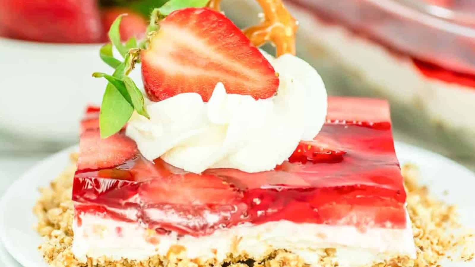 A jello dessert with berries and white layer on a crumb base.