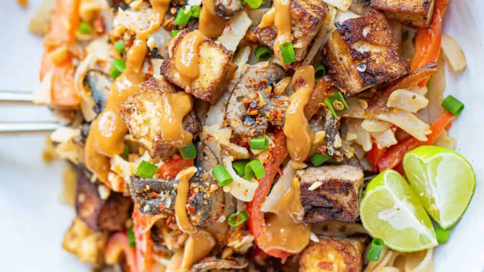 Overhead shot of a bowl of noodles with vegetables and thai peanut sauce.