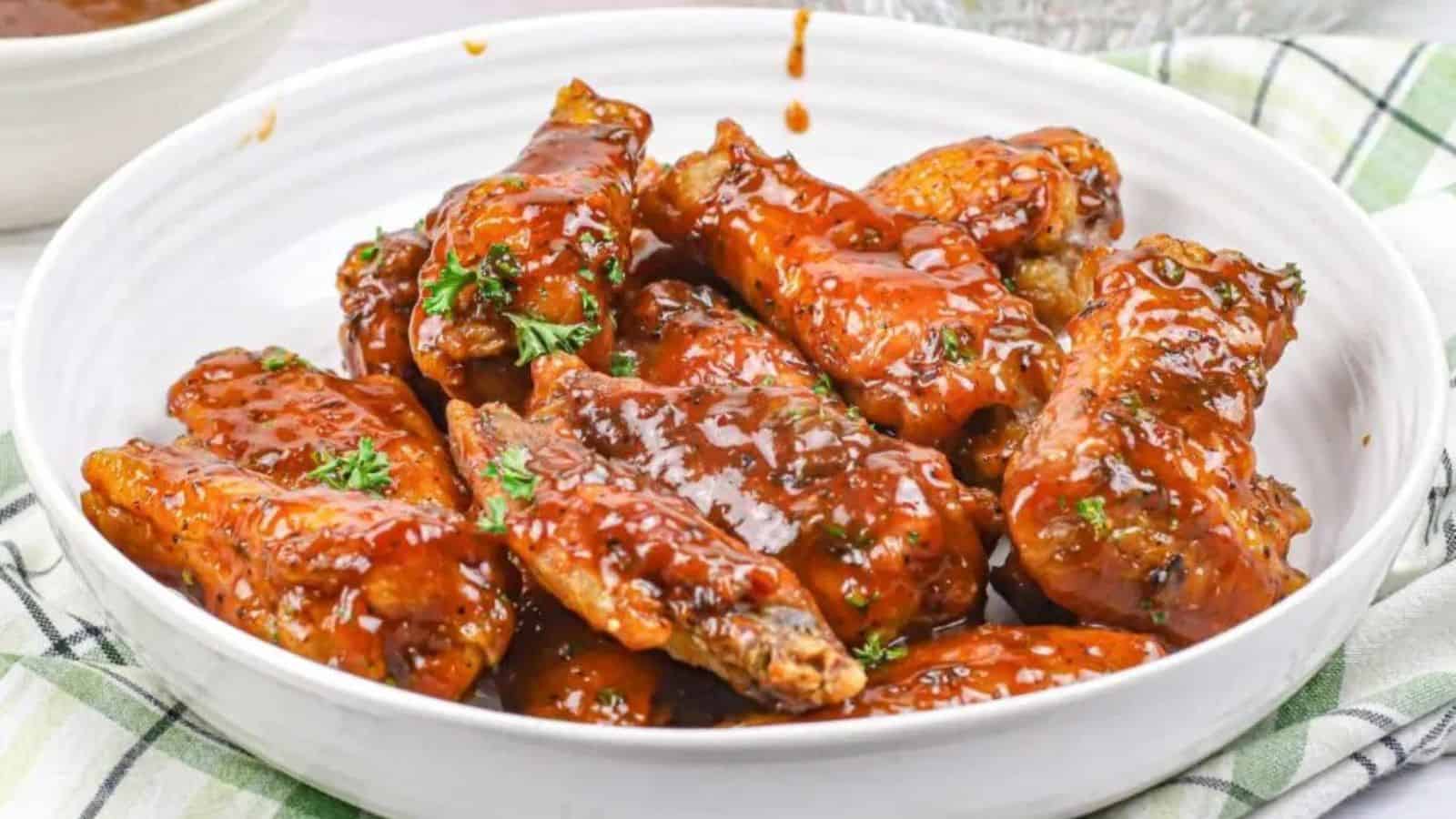 Crispy jerk chicken wings with a spicy glaze, served on a white plate with garnish.